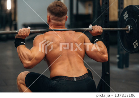 Barbell is on the neck and in hands. Athletic man performing weightlifting exercises in a gym Barbell is on the neck and in hands. Athletic man performing weightlifting exercises in a gym 137815106