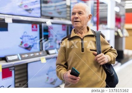 elderly man choosing TV in showroom of electronics store elderly man choosing TV in showroom of electronics store 137815162