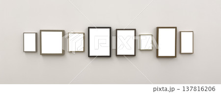 Gallery wall mockup displays series of wooden picture frames aligned on neutral interior background. Gallery wall mockup displays series of wooden picture frames aligned on neutral interior background. 137816206