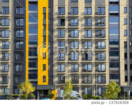 Modern apartment building facade in urban residential area. Condominium exterior with yellow Modern apartment building facade in urban residential area. Condominium exterior with yellow 137816308