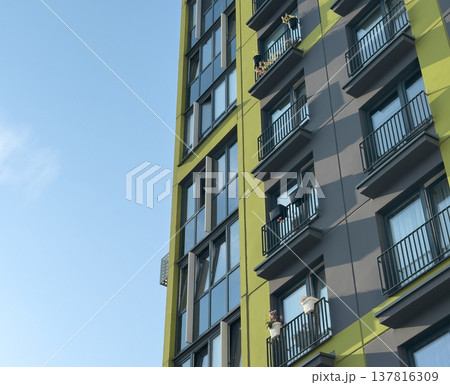Modern apartment building facade in urban residential area. Green and gray exterior with glass Modern apartment building facade in urban residential area. Green and gray exterior with glass 137816309