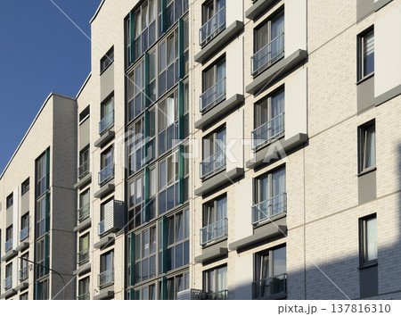 Modern apartment building facade in urban residential area. White brick exterior with glass windows Modern apartment building facade in urban residential area. White brick exterior with glass windows 137816310