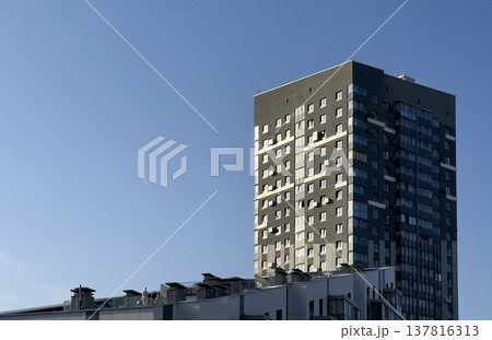 Modern apartment tower building in urban residential area. Gray facade with many windows rises Modern apartment tower building in urban residential area. Gray facade with many windows rises 137816313