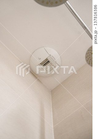 Modern white extractor fan mounted on a light-colored ceiling, providing ventilation and removing humidity and bad odors in a clean, contemporary bathroom interior Modern white extractor fan mounted on a light-colored ceiling, providing ventilation and removing humidity and bad odors in a clean, contemporary bathroom interior 137816386