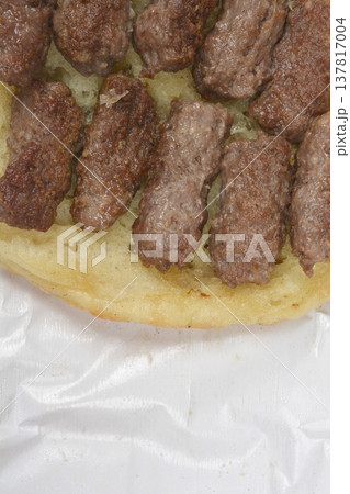 Grilled cevapi meat rolls on lepinja bread close up Grilled cevapi meat rolls on lepinja bread close up 137817004