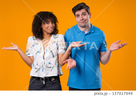 Confused Young Couple Shrugging Shoulders In Uncertainty While Looking At Camera Confused Young Couple Shrugging Shoulders In Uncertainty While Looking At Camera 137817849