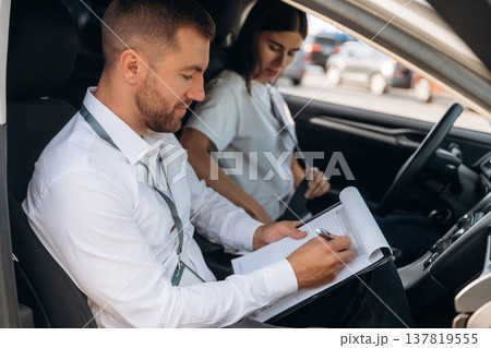 Side view. Woman is with instructor in car, driving school concept Side view. Woman is with instructor in car, driving school concept 137819555