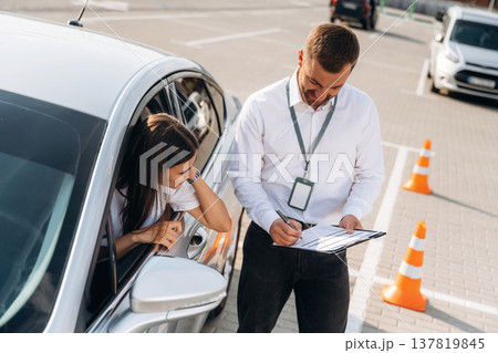 By the guidance of man. Woman is trying to pass exam in the driving school By the guidance of man. Woman is trying to pass exam in the driving school 137819845