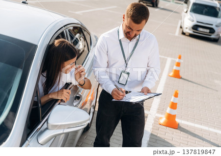 By the guidance of man. Woman is trying to pass exam in the driving school 137819847
