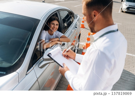 Writing results into notepad. Woman is trying to pass exam in the driving school Writing results into notepad. Woman is trying to pass exam in the driving school 137819869