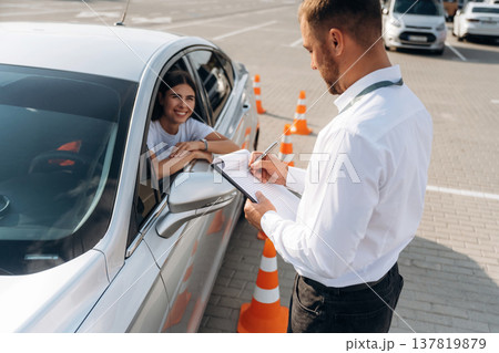 Using pen and writing results into notepad. Woman is trying to pass exam in the driving school Using pen and writing results into notepad. Woman is trying to pass exam in the driving school 137819879
