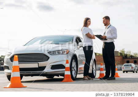 Man instructor in the driving school and woman are outside the car 137819904