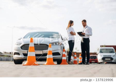 Man instructor in the driving school and woman are outside the car Man instructor in the driving school and woman are outside the car 137819906