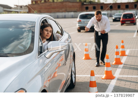 Helping to park the car. Woman is trying to pass exam in the driving school Helping to park the car. Woman is trying to pass exam in the driving school 137819907