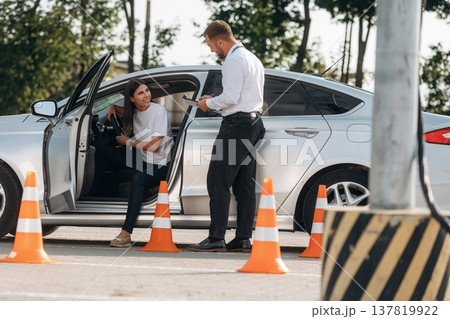 Standing by the car, the results of drive. Woman is trying to pass exam in the driving school Standing by the car, the results of drive. Woman is trying to pass exam in the driving school 137819922