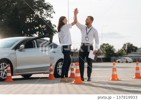 High five, you passed. Woman is trying to pass exam in the driving school 137819933