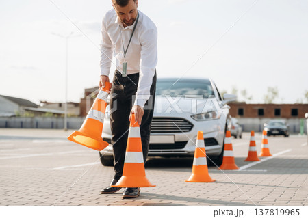 Driving school worker is outdoors near car Driving school worker is outdoors near car 137819965