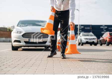 Driving school worker is outdoors near car 137819966