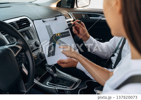 Theoretic knowledge. Woman is with instructor in car, driving school concept 137820073