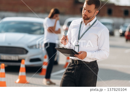 Working with information, holding notepad, woman is sad. Man instructor in the driving school Working with information, holding notepad, woman is sad. Man instructor in the driving school 137820104