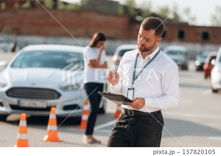 Working with information, holding notepad, woman is sad. Man instructor in the driving school 137820105