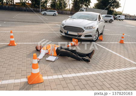 Road worker is got hit by a car, lying down without consciousness on the road 137820163