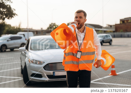 Wellness conception, having fun with the cones. The road worker in orange uniform is with cones near car Wellness conception, having fun with the cones. The road worker in orange uniform is with cones near car 137820167