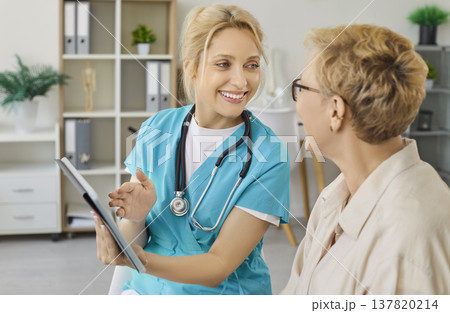 Nurse using tablet to show good health news to older woman on consultation 137820214