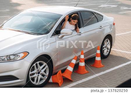 Woman is in the car, in driving school, touching cones by the side of a vehicle Woman is in the car, in driving school, touching cones by the side of a vehicle 137820250