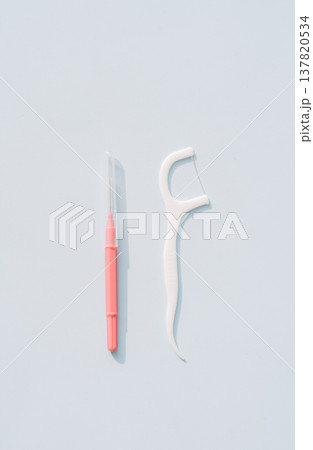 Interdental brush next to a dental floss pick, minimal comparison of interdental cleaning tools 137820534