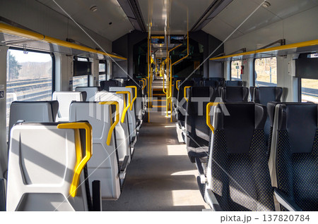 Train interior with empty seats and bright lighting during daytime travel 137820784