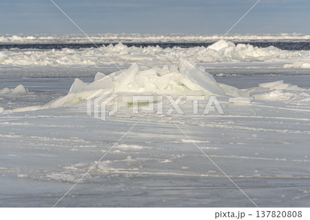 Ice formations float on water in a cold winter landscape near a frozen shore 137820808