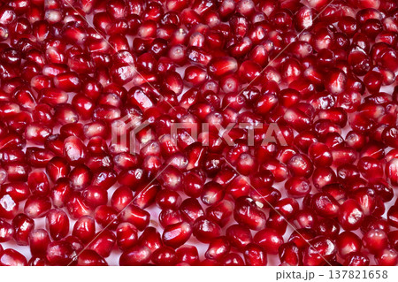 Natural light highlights scattered pomegranate arils with rich colors. Vivid pomegranate seeds spread across textured background emphasizing nutritious and appealing color scheme Natural light highlights scattered pomegranate arils with rich colors. Vivid pomegranate seeds spread across textured background emphasizing nutritious and appealing color scheme 137821658