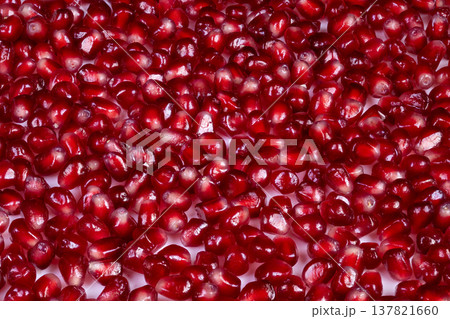Closeup of shimmering pomegranate seeds under dramatic lighting. Detailed view showing vibrant ruby seeds with lustrous surface illuminated dramatically for culinary presentation Closeup of shimmering pomegranate seeds under dramatic lighting. Detailed view showing vibrant ruby seeds with lustrous surface illuminated dramatically for culinary presentation 137821660