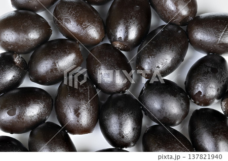 Vivid depiction of piled black olives emphasizing freshness and rustic charm. An artistic arrangement of dark olives highlights their natural flaws and fresh harvest appeal Vivid depiction of piled black olives emphasizing freshness and rustic charm. An artistic arrangement of dark olives highlights their natural flaws and fresh harvest appeal 137821940