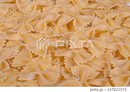 Manufactured bowtie pasta displaying detailed surface finish. Close inspection highlights consistent and meticulous surface craftsmanship in factory manufactured bowtie pasta 137822571