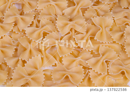 Close up dry farfalle pasta texture, warm natural light, scattered pieces with semolina dust, shallow depth of field, macro pattern ideal for food packaging and recipe visuals 137822586