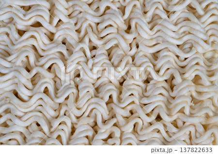 Macro dry instant noodles texture showcasing tight wavy strands and fine flour dust, neutral beige tones, soft diffuse lighting highlighting repetitive pattern and tactile surface 137822633