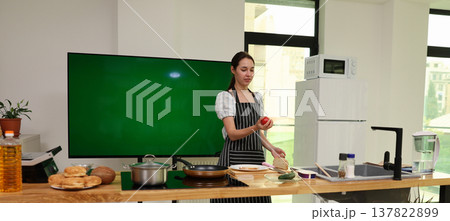 Culinary creativity shines as a young chef prepares a vibrant dish in a modern kitchen filled with fresh ingredients 137822899