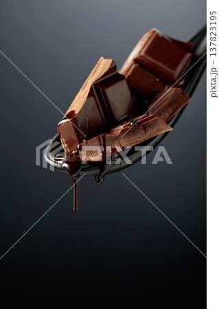 Melting pieces of bitter chocolate on a black background. 137823195
