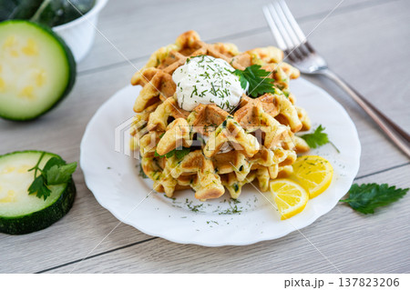 savory zucchini waffles with sour cream and fresh herbs on plate savory zucchini waffles with sour cream and fresh herbs on plate 137823206