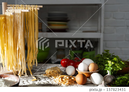 Homemade noodles hanging on wooden dryer rack over messy kitchen table background low angle front view 137823431