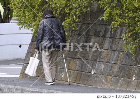 日本の横浜都市景観枝が…下を向いて歩道を歩く杖の高齢女性(マスク姿)、…人生とは…＝横浜市内 137823455