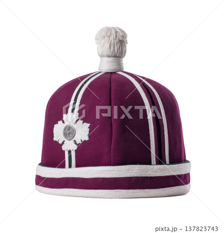 Purple ceremonial hat with white stripes and decorative emblem, featuring white pom pom on top, is displayed against plain background. design is traditional and ornate 137823743