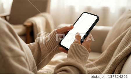 白い画面のスマートフォンを操作する女性の手元のモックアップ素材 137824291