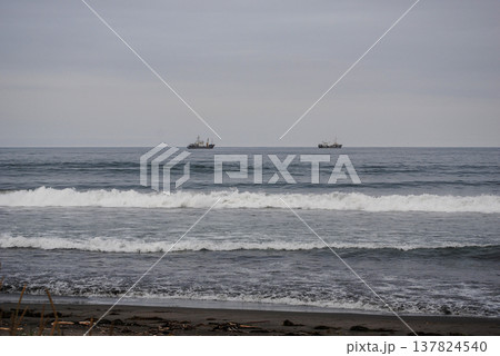 A moody, cloudy day captures ships in a bay along the Kuril Islands' coast. 137824540