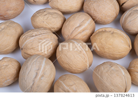 Arranged walnuts on smooth white background. Arrangement of uniformly spaced walnut shells on flawless white backdrop with soft illumination for product presentation Arranged walnuts on smooth white background. Arrangement of uniformly spaced walnut shells on flawless white backdrop with soft illumination for product presentation 137824613