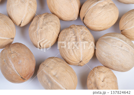 Walnuts display setup. Arrangement of shelled walnuts for catalog presentation. Display configuration of uniformly sized walnuts within shells for digital catalog imagery 137824642