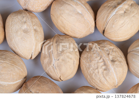 Arranged walnuts under warm lighting. Close view of textured walnut shells. Intimate shot showcasing textured walnut shells with warm illumination and tactile surface emphasis Arranged walnuts under warm lighting. Close view of textured walnut shells. Intimate shot showcasing textured walnut shells with warm illumination and tactile surface emphasis 137824678