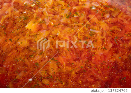 Homemade borscht soup vibrant red, carrot ribbons and cabbage pieces in clear beet broth, cooling in pot for storage, nutritious prep for busy weeknight dinners 137824765